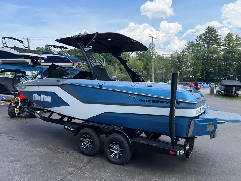 Slide: The Image of A blue 2025 Malibu Wakesetter 22 MXZ sits on a trailer in a parking lot. - 17