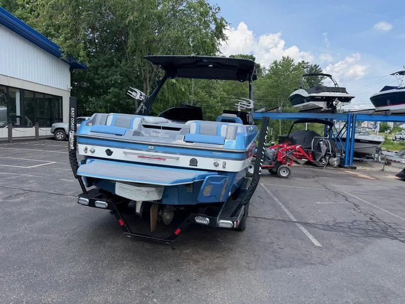 Slide: The Image of A 2025 Malibu Wakesetter 22 MXZ is parked on a lot. It features a blue and white design. - 9