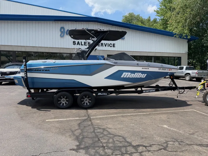 Slide: The Image of A 2025 Malibu Wakesetter 22 MXZ on a trailer in front of a building labeled "Sales Service." - 3
