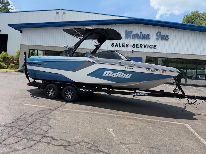 Slide: The Image of A 2025 Malibu Wakesetter 22 MXZ on a trailer in front of a sales and service building. - 2