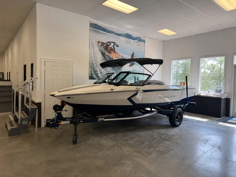 The Image of A MasterCraft ProStar 2026 boat is displayed in a showroom on a trailer. - 1