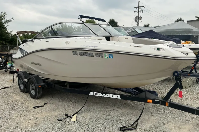 Slide: The Image of A 2010 Sea-Doo Sport Boat 210 Challenger SE on a trailer, parked on a gravel lot. - 2