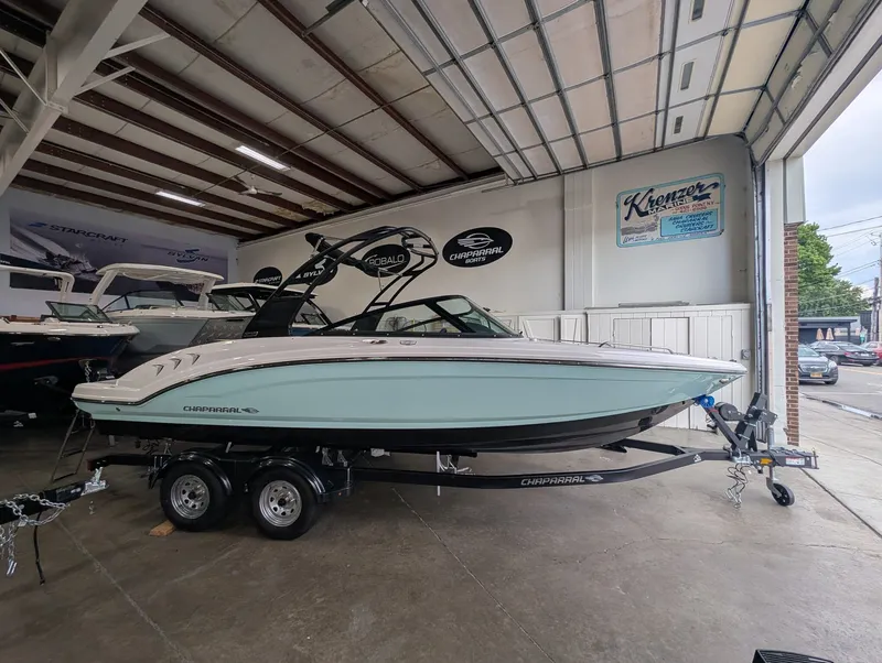 The Image of A 2027 Chaparral SSI 23 boat on a trailer inside a showroom. - 1