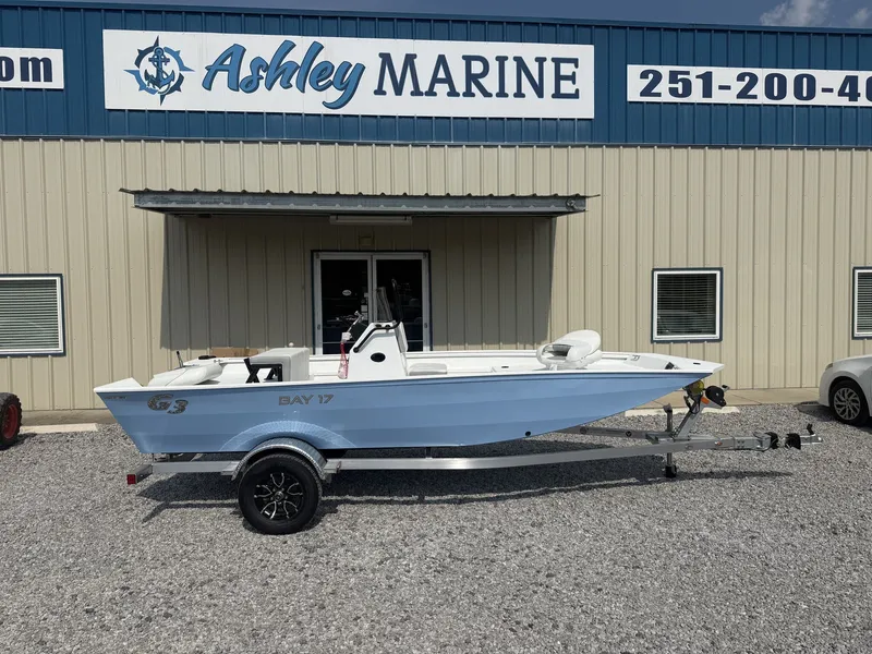 The Image of A white G3 Bay 17 boat on an aluminum trailer in front of a building with "Ashley Marine" signage. - 1