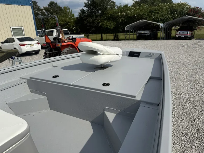 Slide: The Image of A gray boat with a white seat on the deck, parked on a gravel lot. - 2