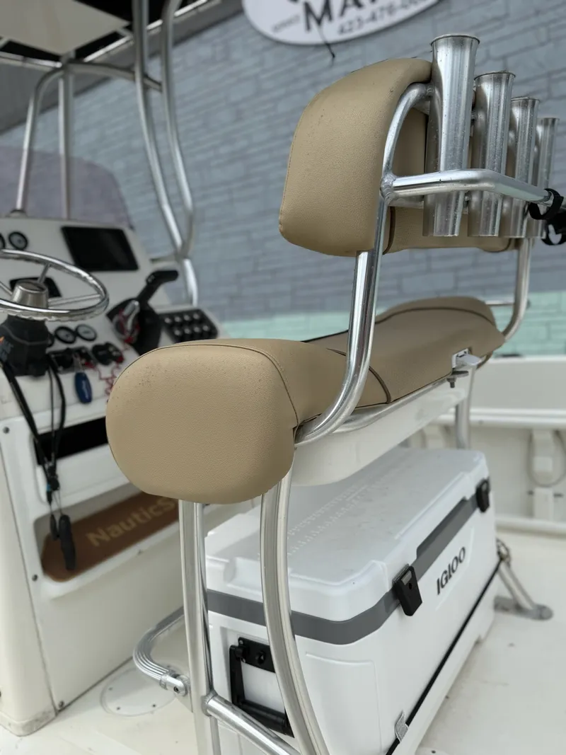 Slide: The Image of The image shows the cockpit of a 2019 NauticStar 231 HYBRD CC with beige upholstery and an Igloo cooler. - 14