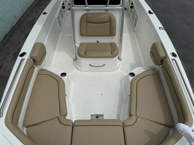 Slide: The Image of The image shows the cockpit of a 2019 NauticStar 231 HYBRD CC with beige upholstery. - 12