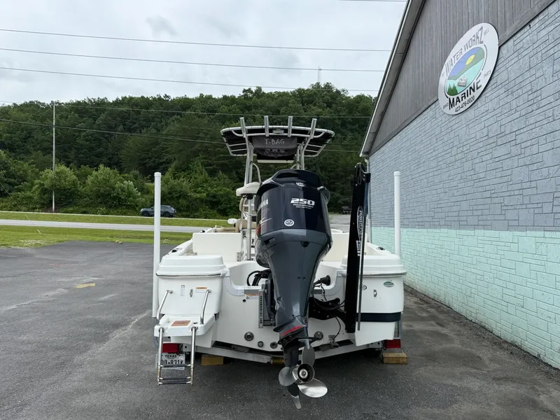 Slide: The Image of A 2019 NauticStar 231 HYBRD CC with an outboard motor, parked beside a building. - 5
