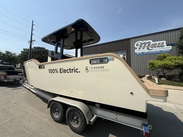 Slide: The Image of A modern electric boat, the X Shore Eelex 8000, sits on a trailer outside a building. - 7