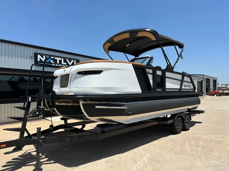 Slide: The Image of A modern pontoon boat with a black canopy and white sides sits on a trailer in front of a building. - 2