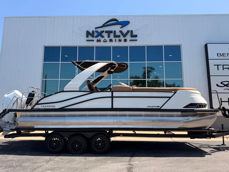 Slide: The Image of A 2027 Harris Grand Mariner 250 on a trailer in front of a modern building. - 2