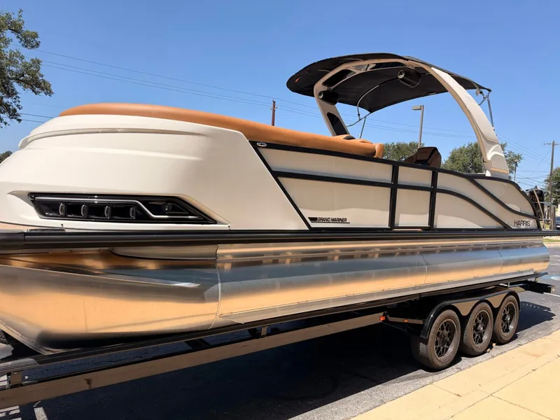 Slide: The Image of A sleek pontoon boat with a modern design, sitting on a trailer. It features a sunshade and comfortable seating. - 3