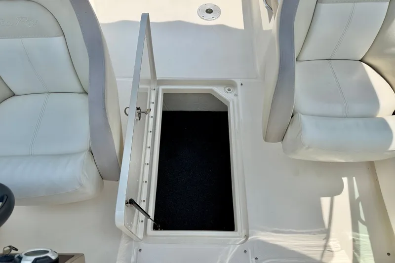 Slide: The Image of 2013 Sea Ray 260 Sundeck interior with open storage compartment between white seats. - 31