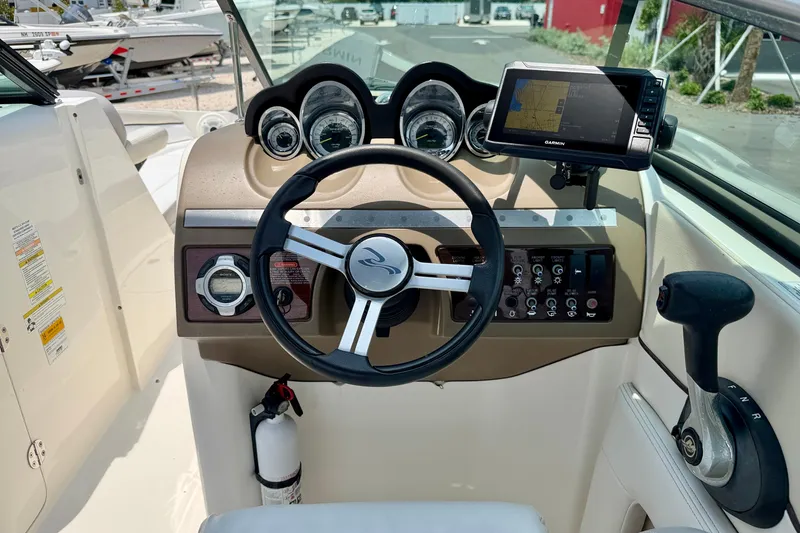 Slide: The Image of 2013 Sea Ray 260 Sundeck dashboard with steering wheel, gauges, and Garmin GPS. - 13