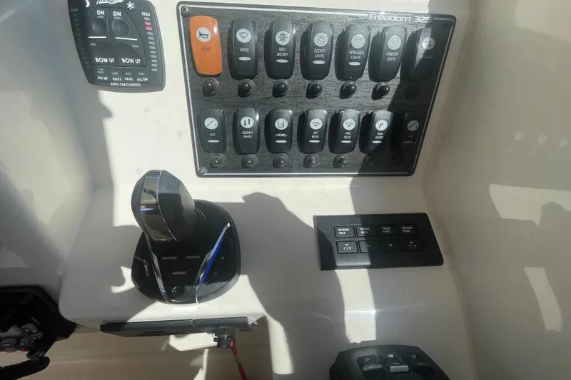 Slide: The Image of Control panel of 2021 Grady-White Freedom 325 boat with switches and throttle. - 16
