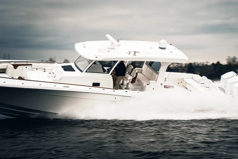 Slide: The Image of 2027 HCB 48 Campeon boat cruising swiftly on water under cloudy skies. - 4