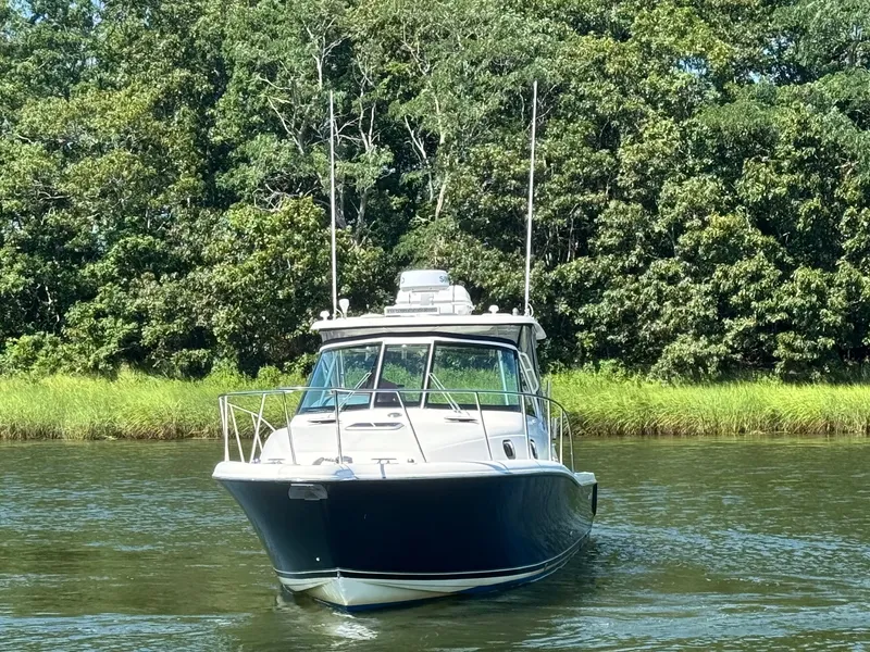 Slide: The Image of 2006 Pursuit 3370 Offshore on a calm river, surrounded by lush greenery. - 4