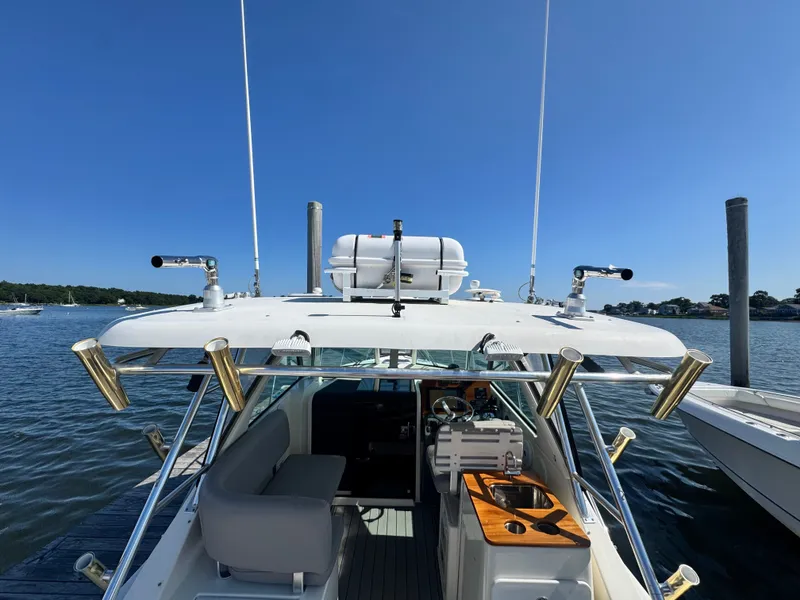 Slide: The Image of The image shows a 2006 Pursuit 3370 Offshore boat docked. It features an open cabin with seating and fishing rod holders. - 17
