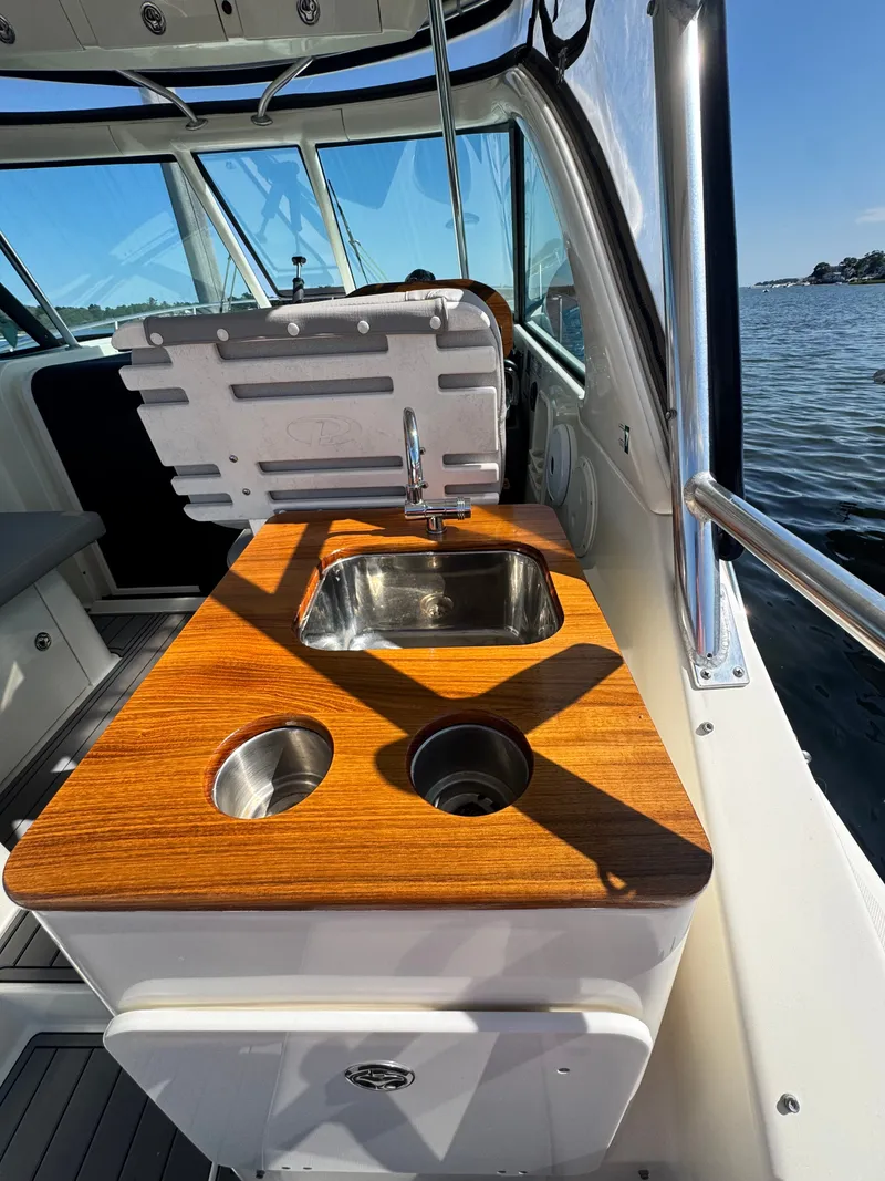 Slide: The Image of The 2006 Pursuit 3370 Offshore features an outdoor kitchenette with a sink and wooden countertop. - 14