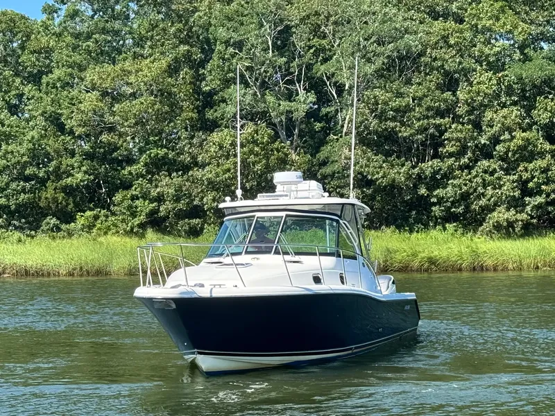 Slide: The Image of A 2006 Pursuit 3370 Offshore cruising on calm waters, surrounded by lush greenery. - 5