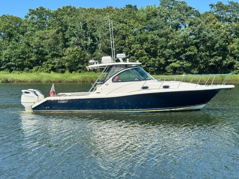 The Image of A 2006 Pursuit 3370 Offshore boat cruising on calm water, surrounded by trees. - 0