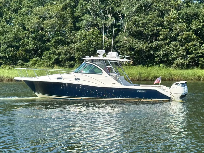 Slide: The Image of A 2006 Pursuit 3370 Offshore cruising on a calm river, surrounded by lush greenery. - 7