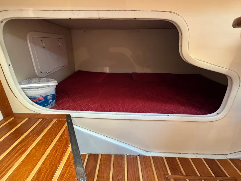 Slide: The Image of A cabin with a red bed and wooden floor on a 2006 Pursuit 3370 Offshore boat. - 25