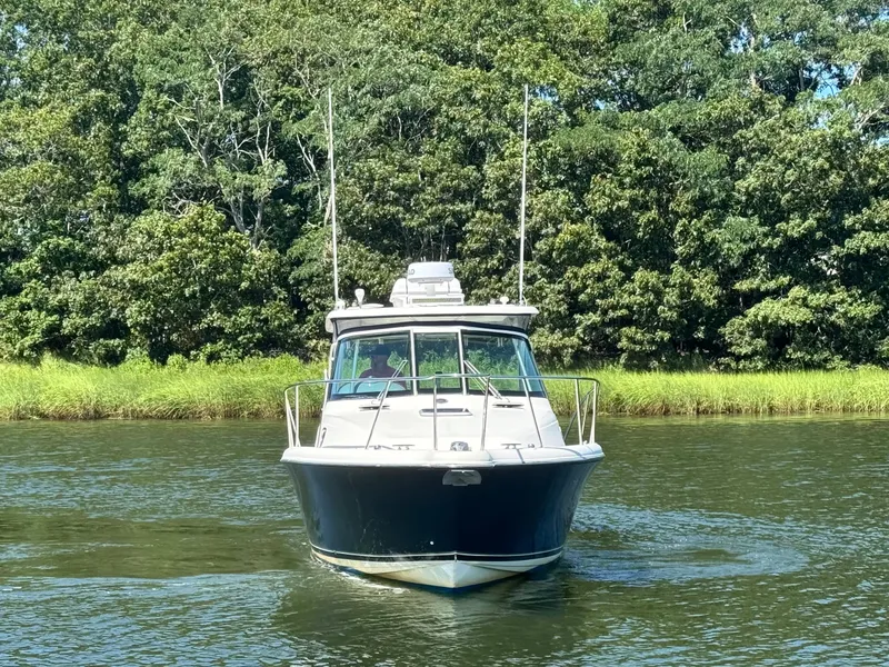Slide: The Image of A 2006 Pursuit 3370 Offshore boat cruising on a calm river with a wooded shoreline. - 3