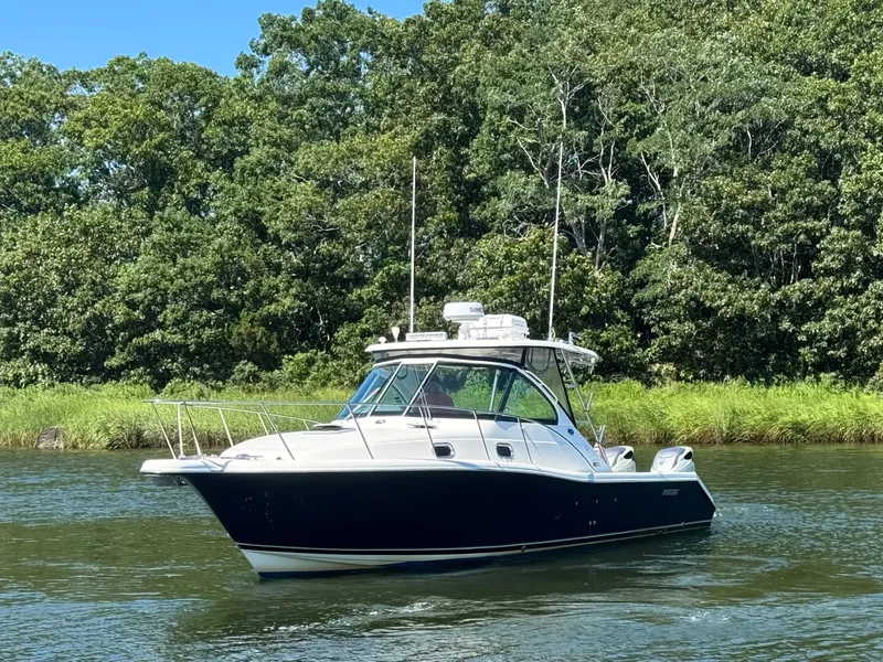 Slide: The Image of A 2006 Pursuit 3370 Offshore boat cruising on a calm river, surrounded by lush greenery. - 6