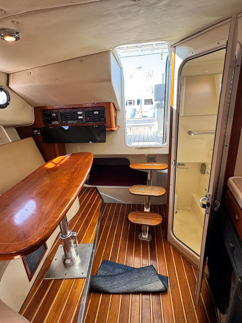 Slide: The Image of Interior of a 2006 Pursuit 3370 Offshore with wood flooring, table, and steps to the cabin. - 26