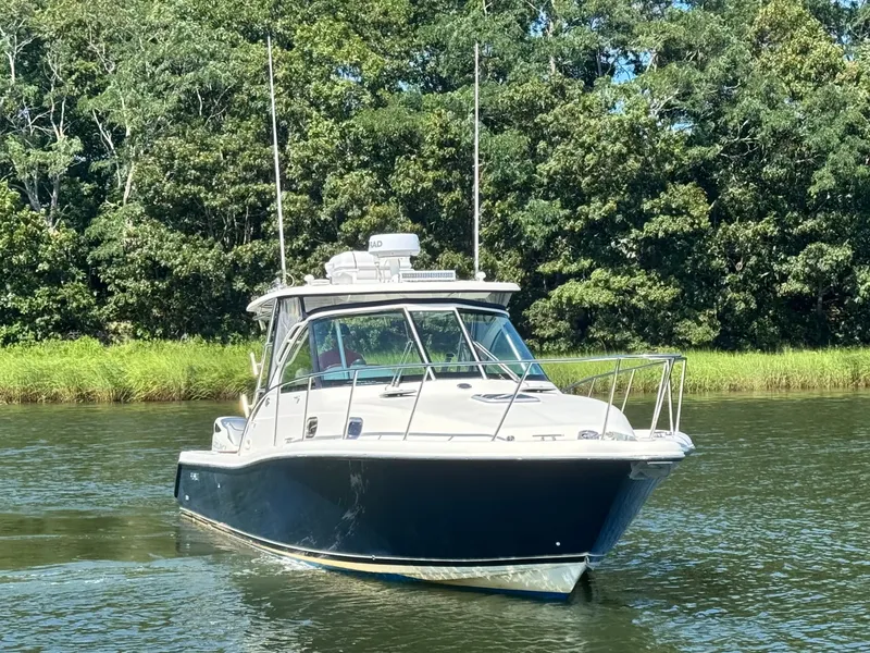 Slide: The Image of A 2006 Pursuit 3370 Offshore boat cruising on calm water, surrounded by trees. - 2