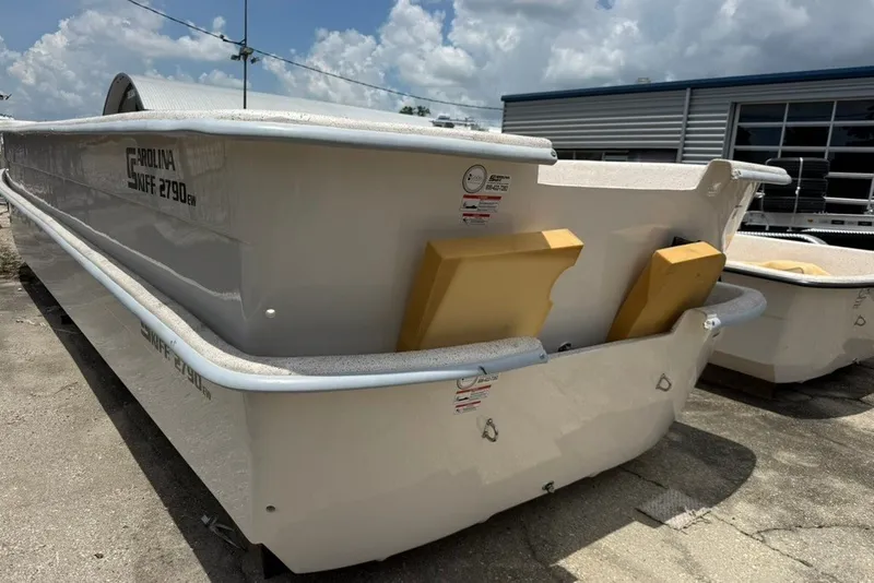 Slide: The Image of 2027 Carolina Skiff 2790 boat, white exterior, docked outdoors under a cloudy sky. - 11
