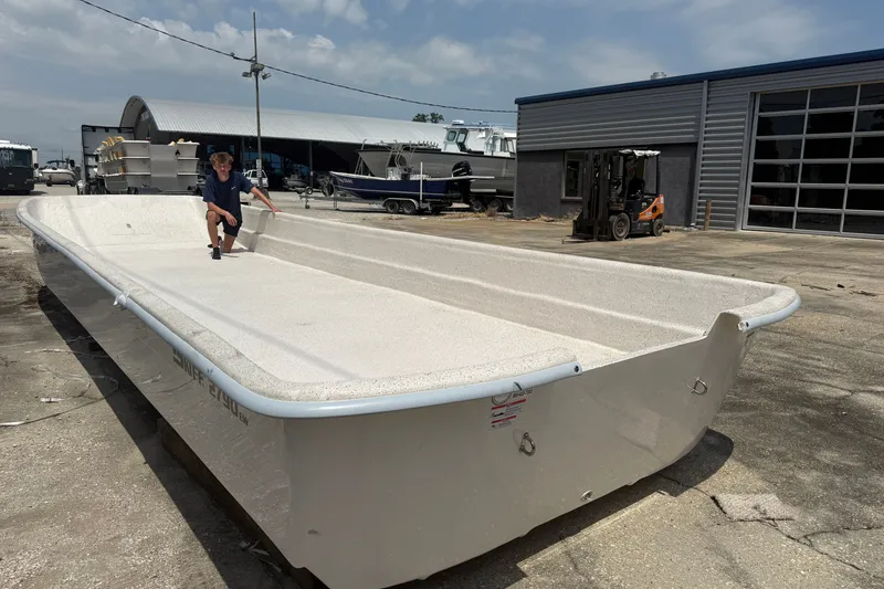 Slide: The Image of 2027 Carolina Skiff 2790 boat hull in a shipyard, person inspecting. - 2