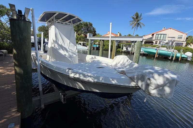 Slide: The Image of A 2015 Ranger boat docked on a lift, covered, with waterfront homes in the background. - 8