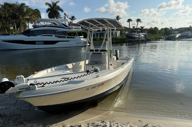 Slide: The Image of A 2015 Ranger boat docked on a sandy shore with yachts in the background. - 5
