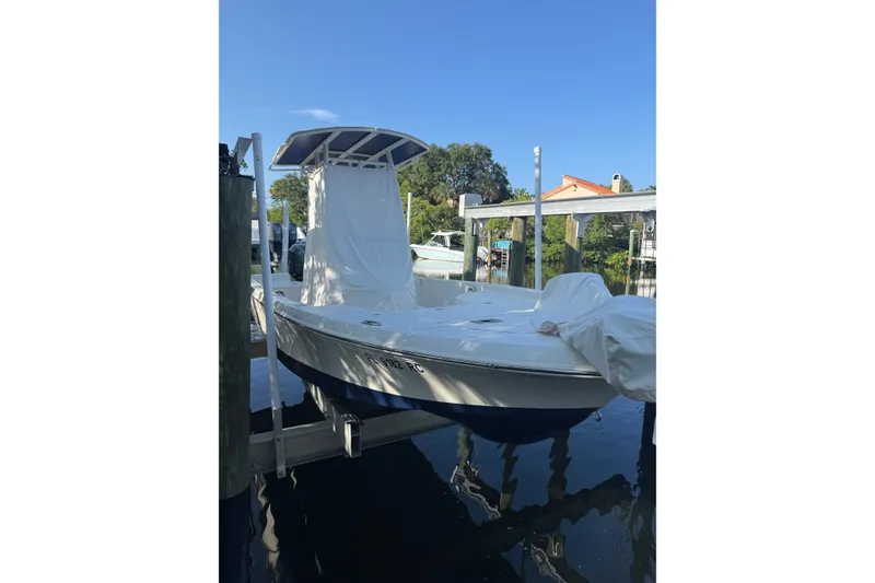 Slide: The Image of 2015 Ranger boat docked, covered, with blue hull and white top under clear sky. - 18
