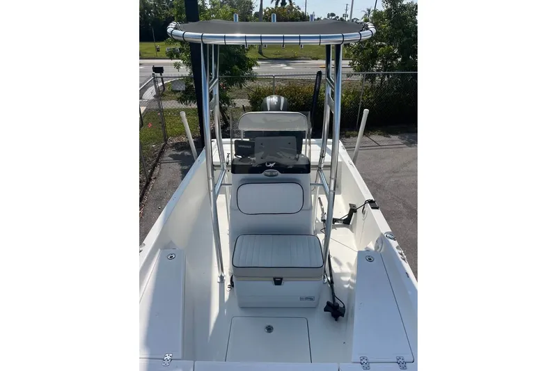 Slide: The Image of 2016 Mako 19 CPX boat interior with seating and console, parked outdoors. - 7