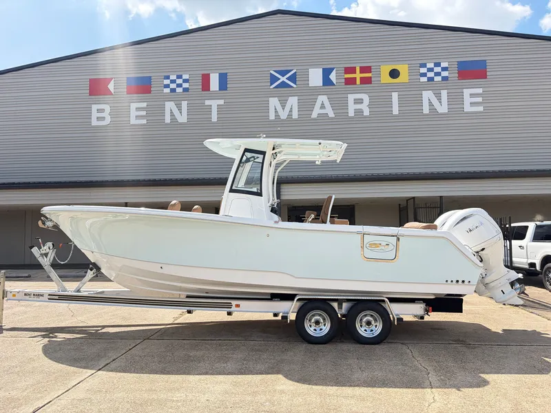 The Image of A 2027 Sea Hunt Ultra 265 SE boat on a trailer in front of a building with flags. - 1