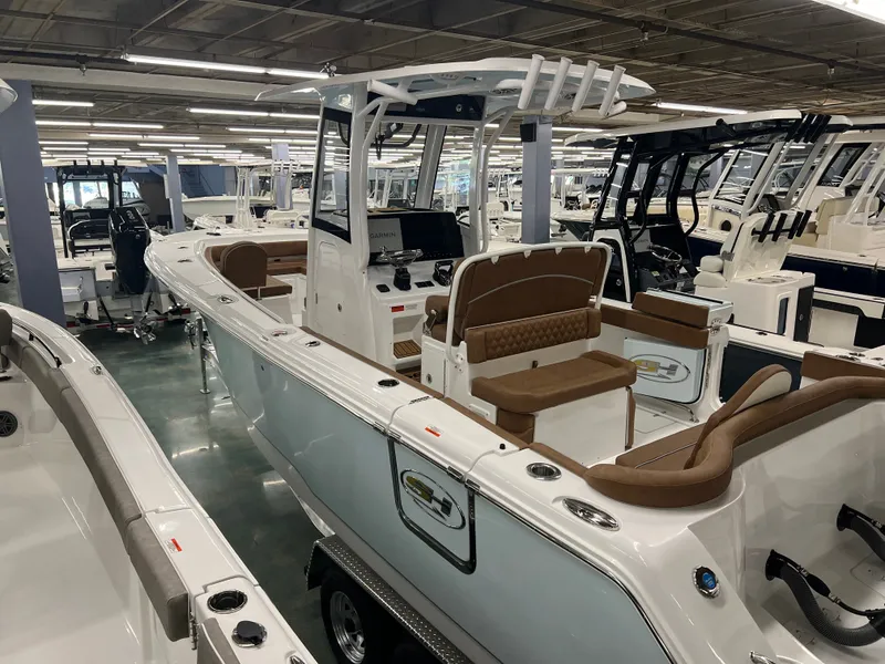 Slide: The Image of A modern 2027 Sea Hunt Ultra 265 SE in a showroom. It features sleek design, brown seating, and a spacious deck. - 19