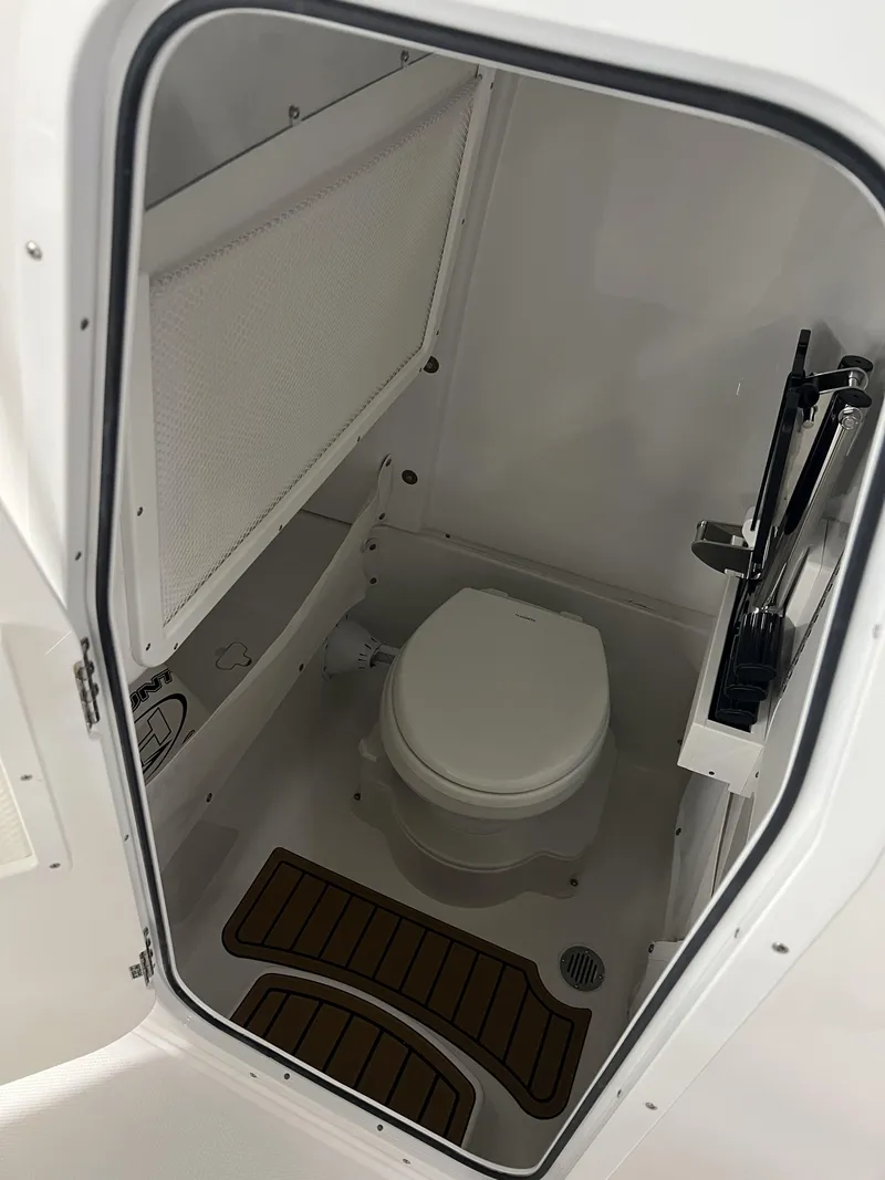Slide: The Image of The image shows a compact boat toilet with white walls and wood floor accents. - 11
