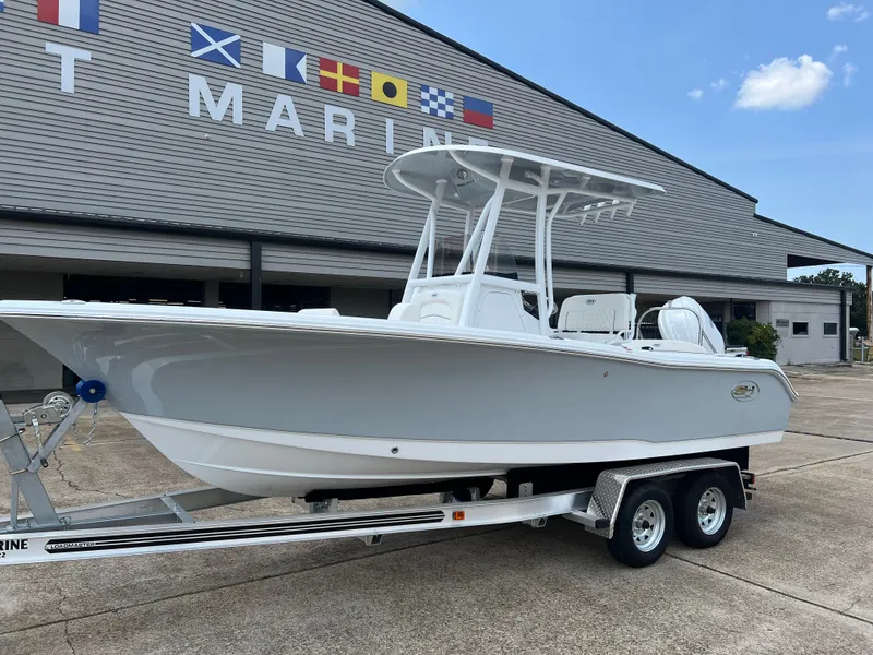 Slide: The Image of A 2027 Sea Hunt Ultra 219 boat on a trailer in front of a building with flags. - 2