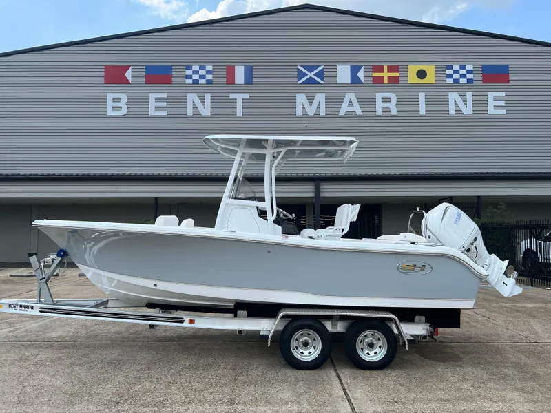 The Image of A 2027 Sea Hunt Ultra 219 boat on a trailer in front of a building with flags. - 1