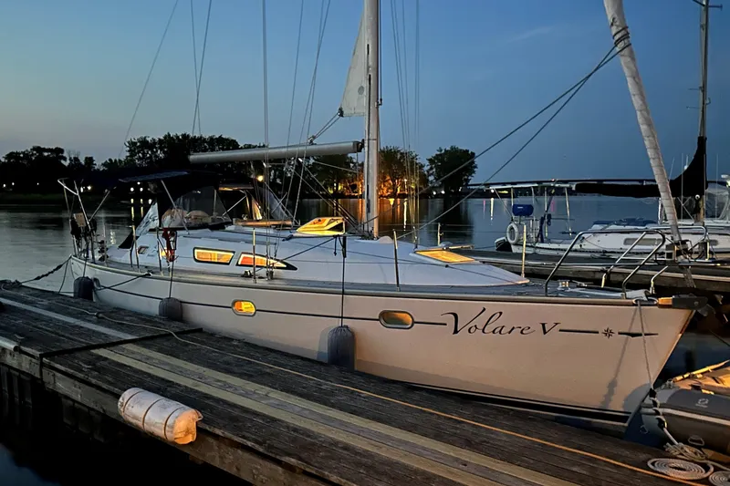 The Image of 2004 Jeanneau Sun Odyssey 37 sailboat docked at sunset, illuminated cabin lights. - 0