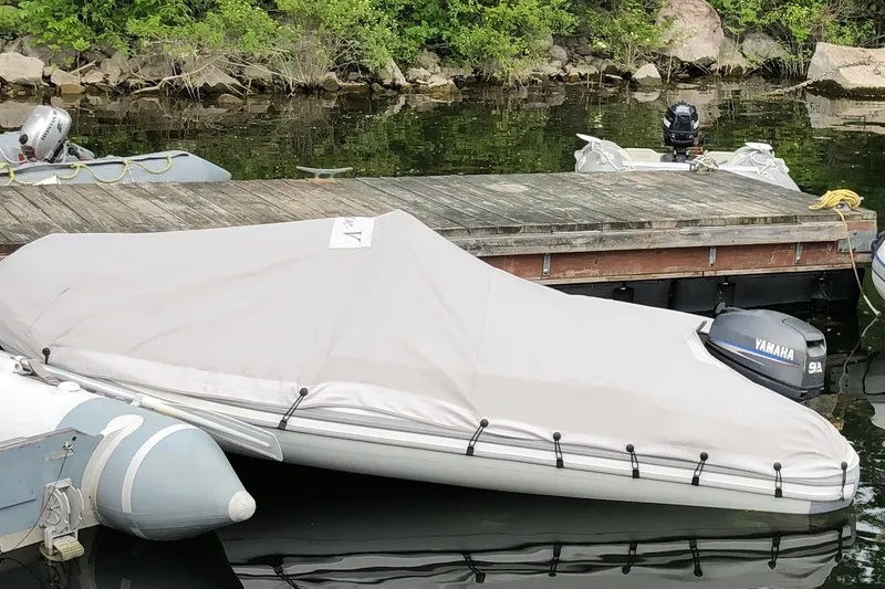 Slide: The Image of Covered inflatable boat with Yamaha motor docked near wooden pier. - 28