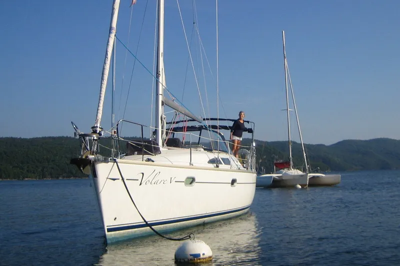 Slide: The Image of 2004 Jeanneau Sun Odyssey 37 sailboat anchored on calm water with scenic background. - 0