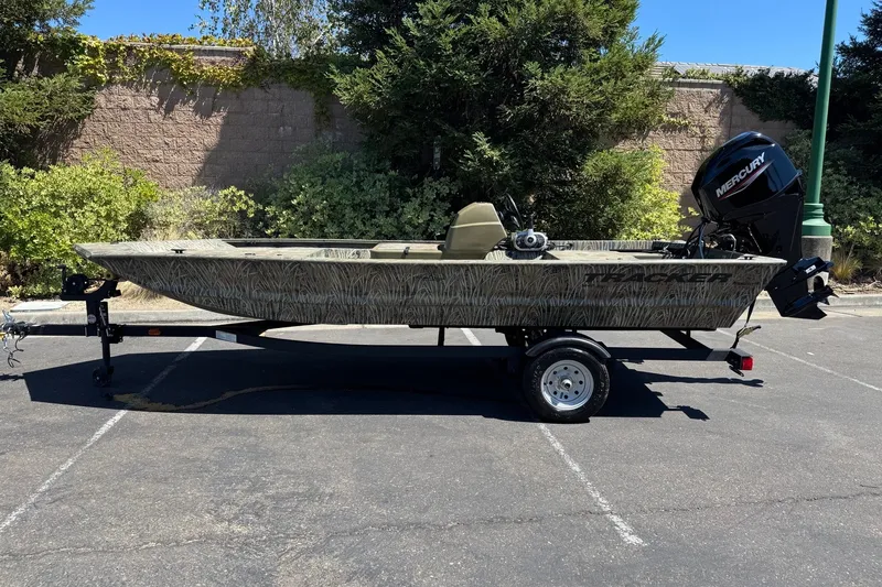 The Image of 2026 Tracker Grizzly 1648 SC boat on trailer, parked outdoors with Mercury outboard motor. - 0