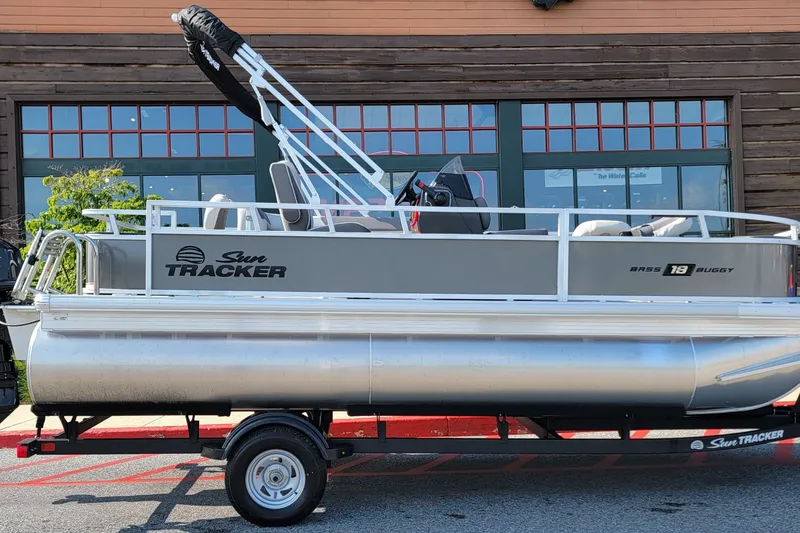 The Image of 2026 Sun Tracker Bass Buggy 18 DLX pontoon boat on trailer, parked outdoors. - 0