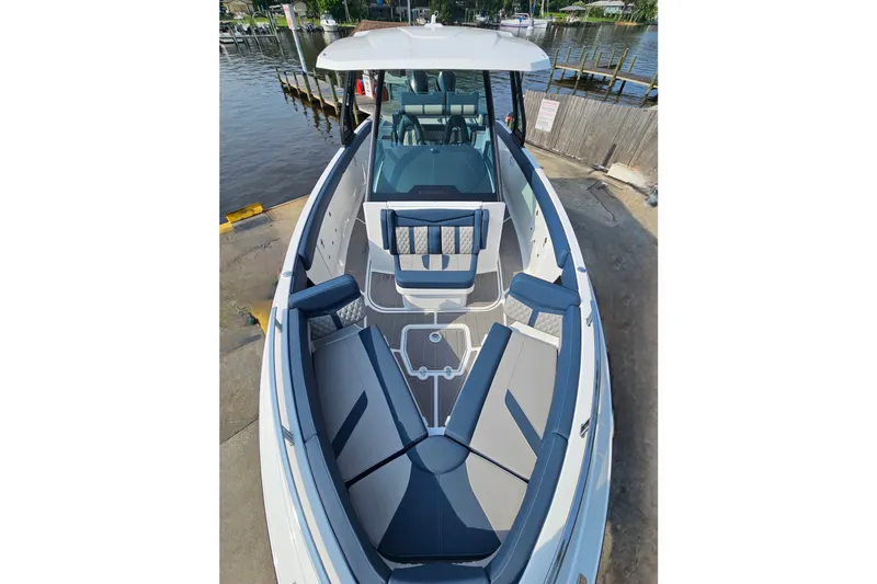 Slide: The Image of 2026 Monterey Elite 30 OB boat with spacious seating, docked by the water. - 27