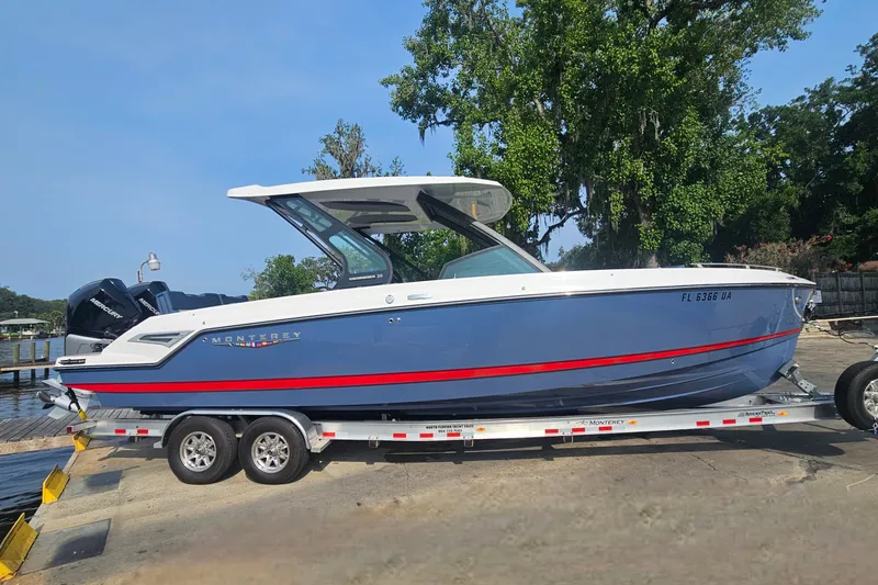 Slide: The Image of 2026 Monterey Elite 30 OB boat on trailer, blue and white design, dockside setting. - 2
