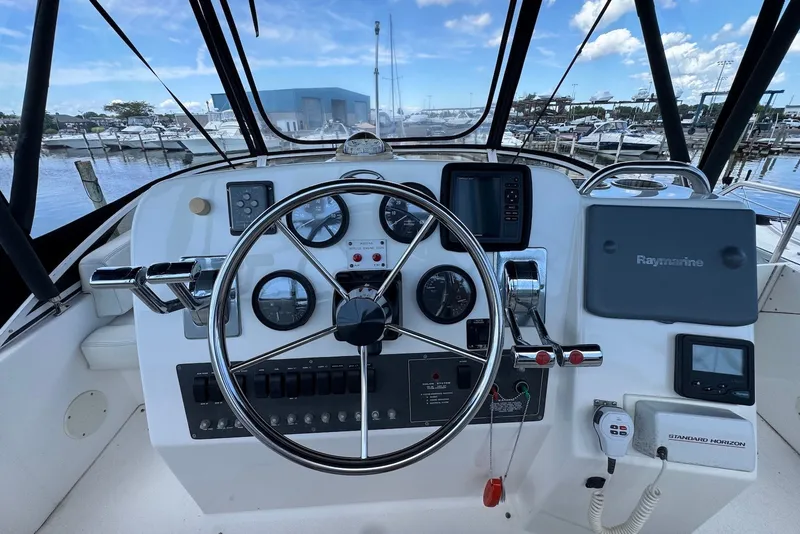 Slide: The Image of 1999 Silverton 351 Sedan helm with gauges, steering wheel, and navigation equipment at marina. - 11